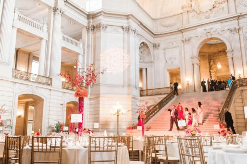 Grand luxury venue interior with sweeping staircase, elegant floral decor, and upscale wedding event ambiance