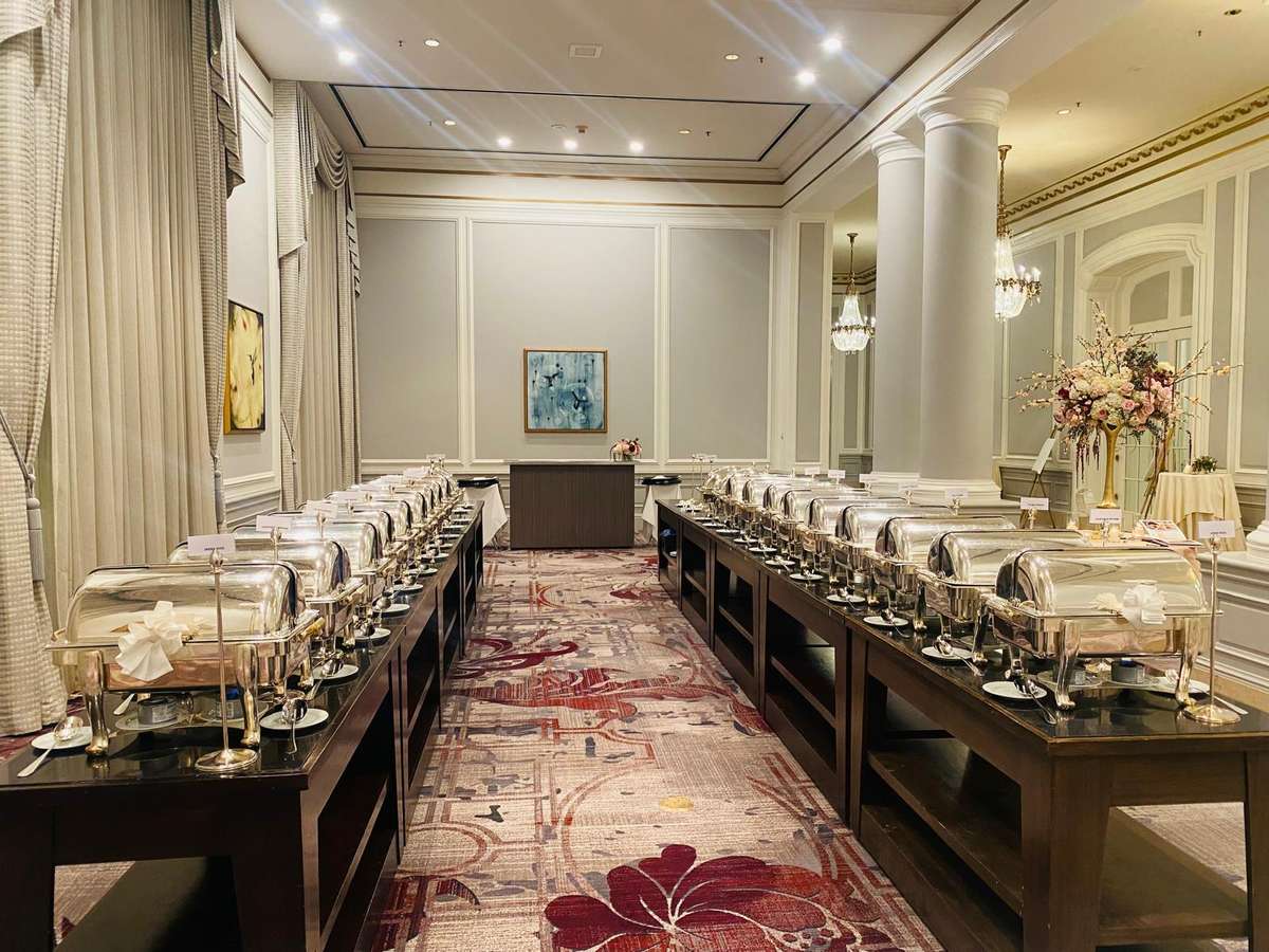 Elegant banquet buffet setup with chafing dishes, floral arrangements, and upscale event dining in a luxury ballroom venue