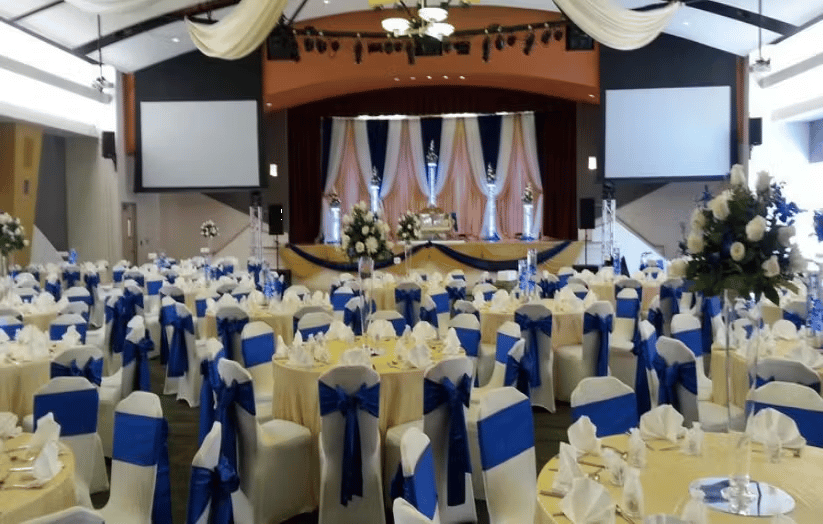 Elegant banquet hall setup with blue and gold chair decor, formal table settings, and upscale wedding reception atmosphere