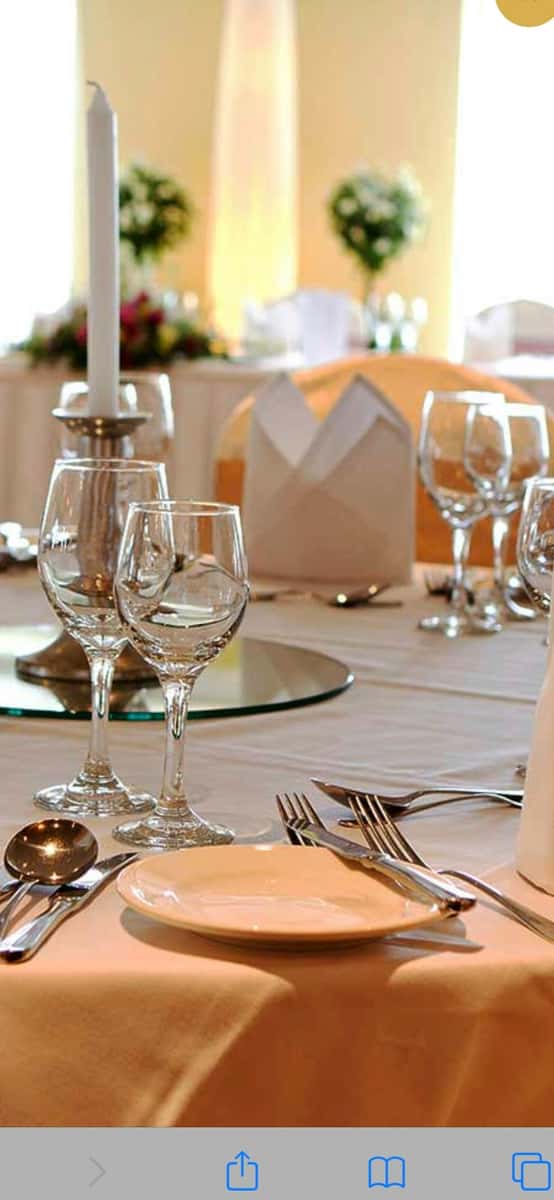 Elegant banquet table setting with wine glasses, silver cutlery, a white napkin, and a candle centerpiece on a white tablecloth.