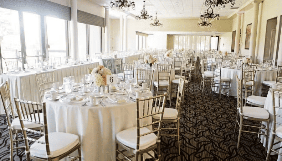 Luxury ballroom reception with elegant table settings, gold chairs, and sophisticated wedding decor