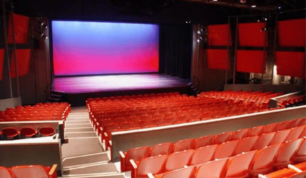 Modern theater auditorium with red seating and large projection screen for entertainment and private events