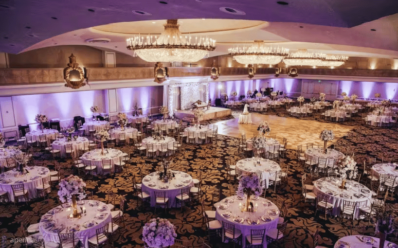 Elegant ballroom reception with round banquet tables, chandeliers, and upscale wedding event decor
