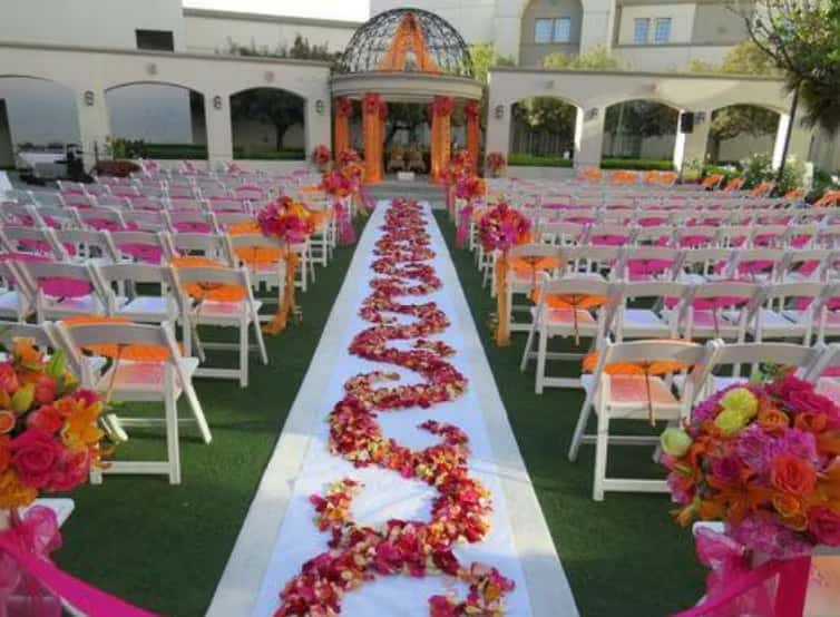 Outdoor wedding ceremony setup with floral aisle decor, colorful seating, and elegant event venue atmosphere