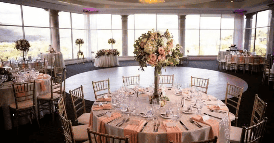 Upscale wedding reception table with blush floral centerpiece, elegant place settings, and natural window lighting