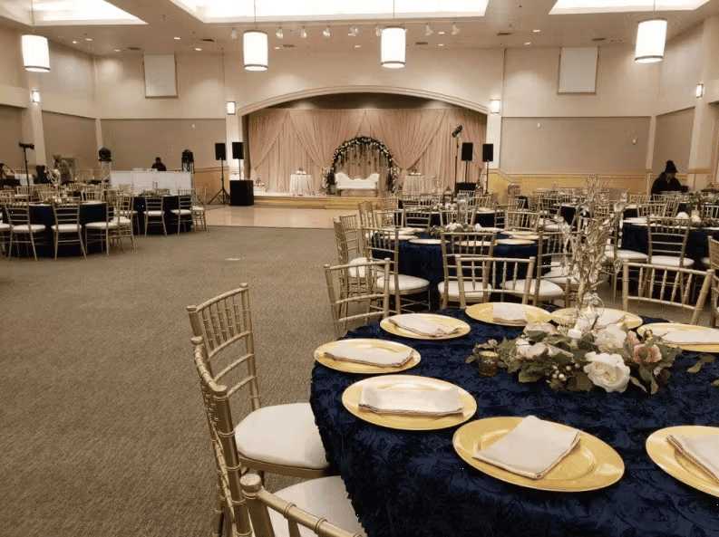 Modern banquet hall with round dining tables, gold chairs, and sophisticated event venue setup
