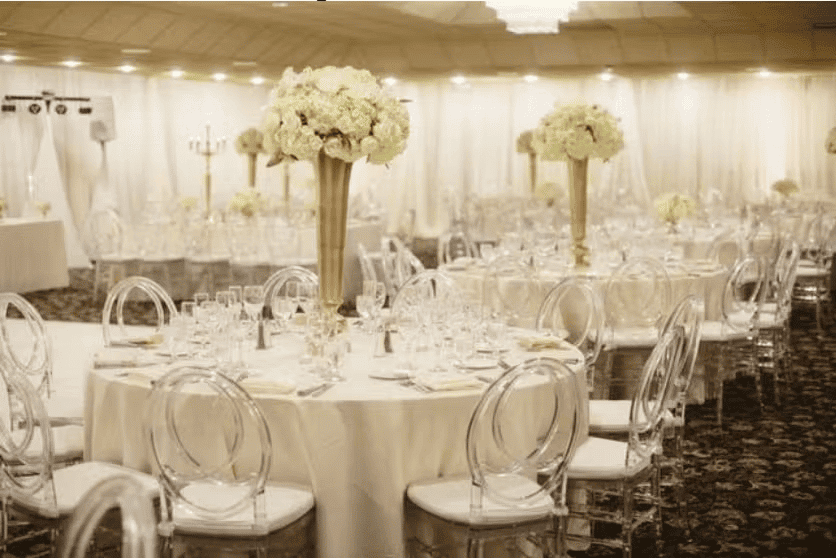 Elegant wedding reception table setup with floral centerpieces, gold chiavari chairs, and upscale ballroom decor