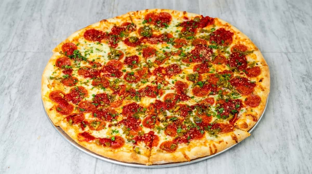 Pepperoni pizza topped with sliced green jalapeños and parsley.