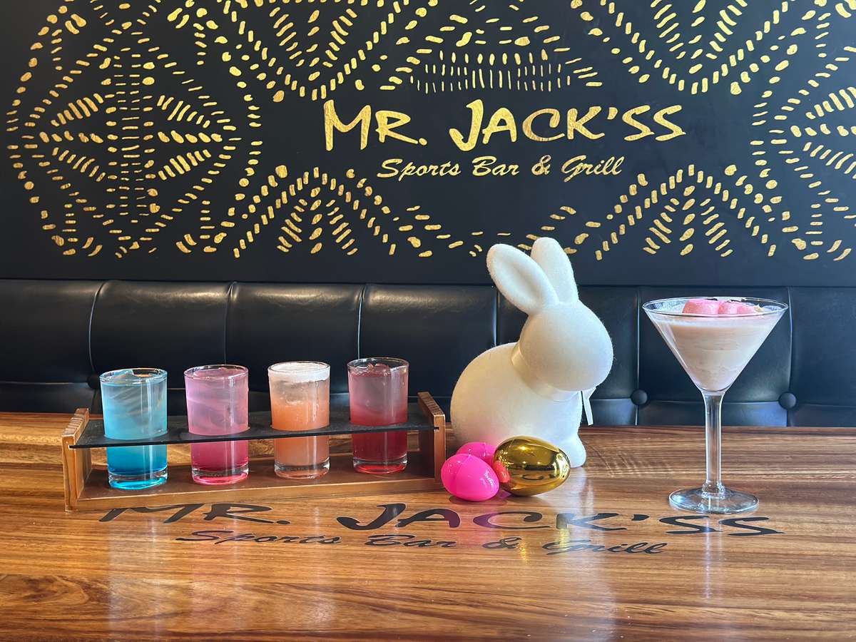Easter drinks are displayed at Mr. Jack'ss Sports Bar & Grill, with a bunny and colorful Easter eggs. The bar's logo and name are featured in gold.