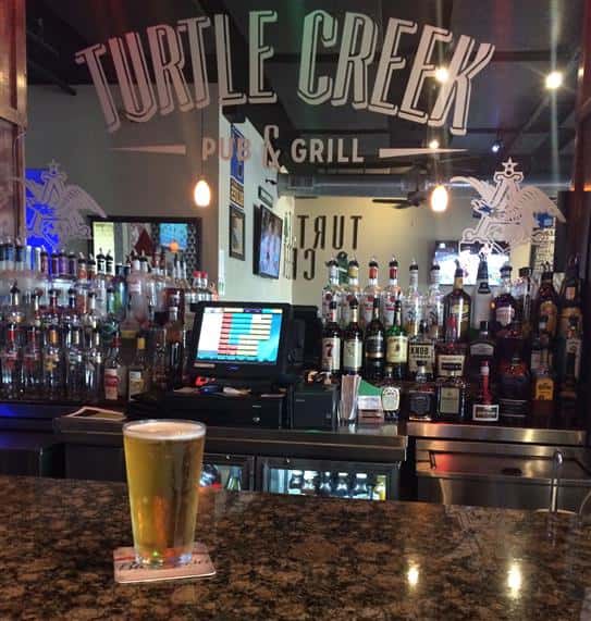 pint of beer on the bar with turtle creek pub and grill sign on bar mirror wall