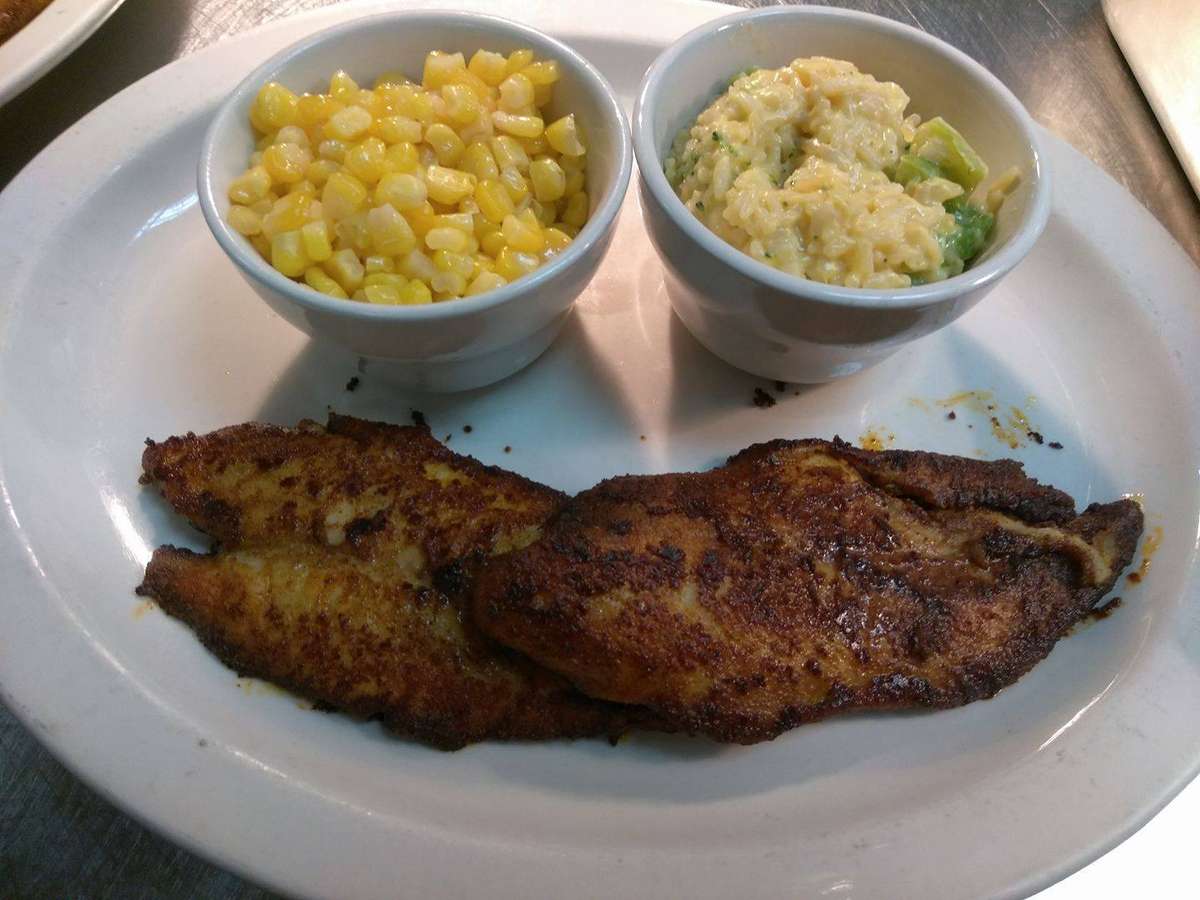 Seasoned grilled fish on plate with side of corn and mashed potato