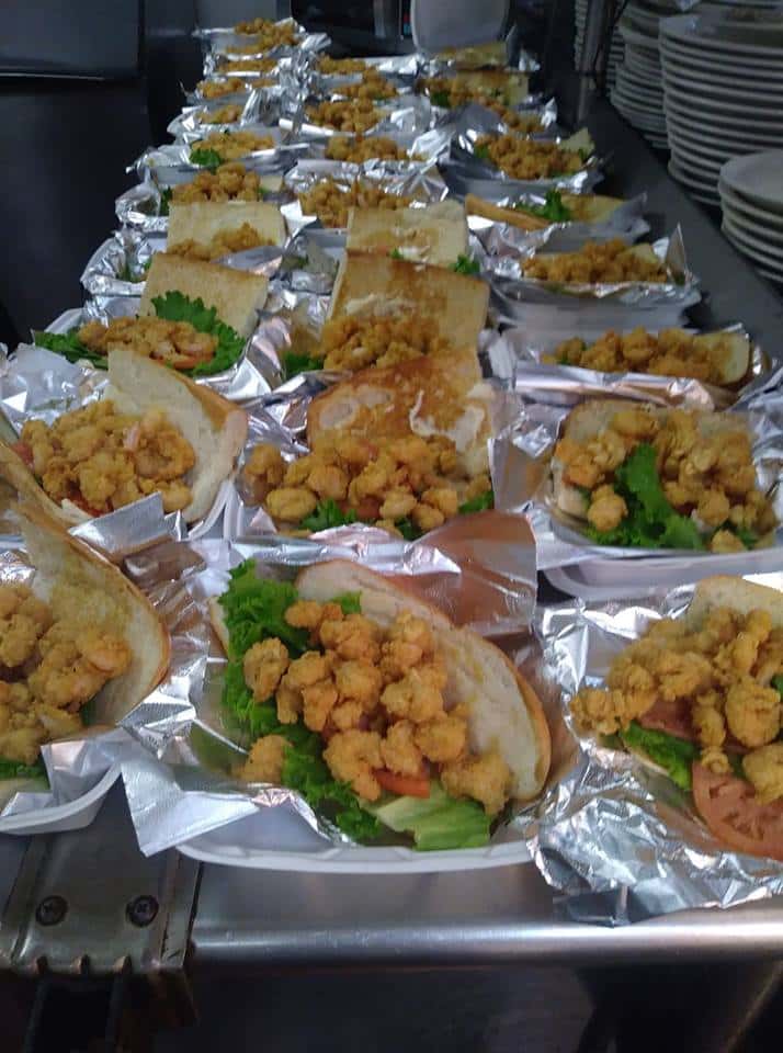 A table filled with premade sandwiches with fried shrimp poboys