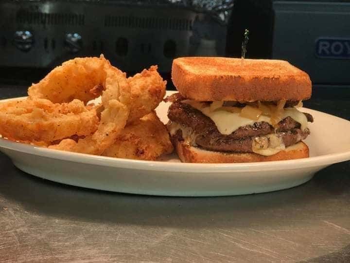 Double cheeseburger with diced onions on thick texas toast with side of onion rings