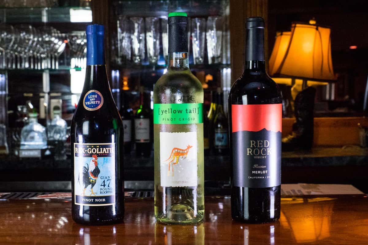 three assorted bottles of wine lined up on the bar