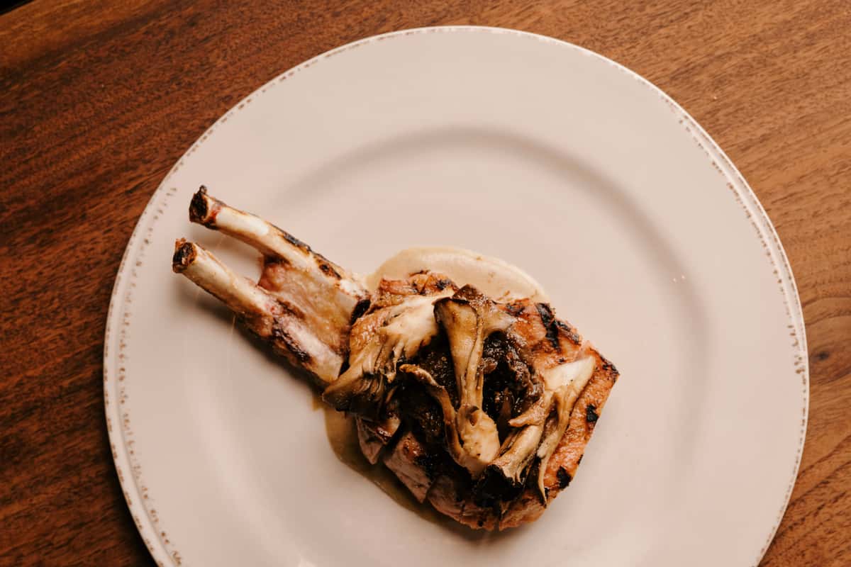Double bone-in pork chop topped with roasted mushrooms and served over a creamy sauce.