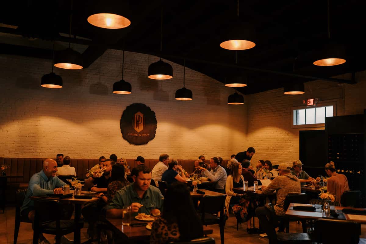Warmly lit dining room at Prime & Pint filled with guests enjoying dinner, creating a cozy and lively steakhouse atmosphere.