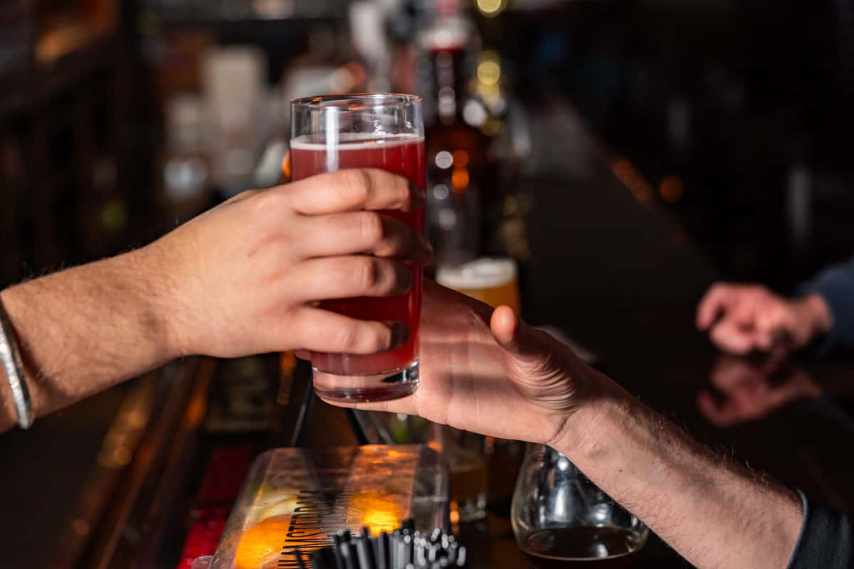 Server's hands giving a glass of beer to a patron