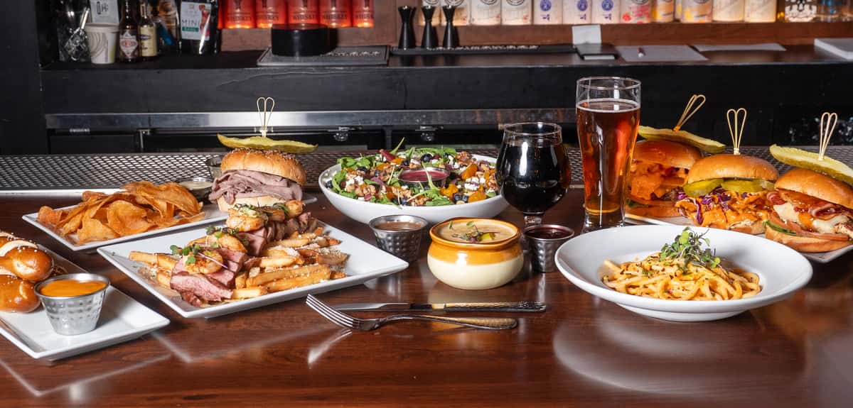 A variety of drinks, sandwiches, burgers and sides on a table