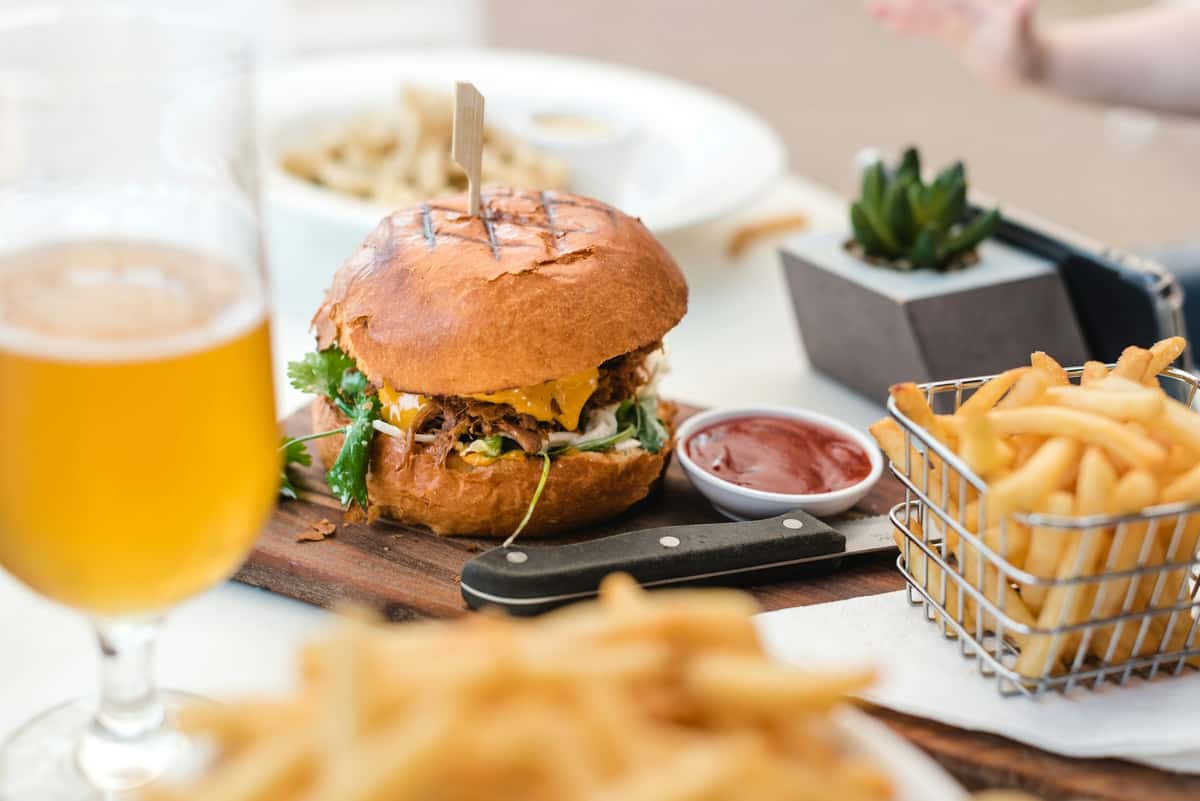 Here's a delicious scene: a burger presented on a wooden board with fries and a beer. This photo is part of the restaurant's gallery.