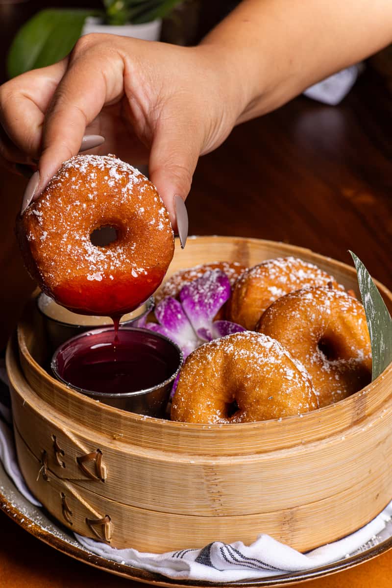 Japanese-style mochi donuts served in a bamboo steamer with dipping sauce at Kapow! Noodle Bar, a modern Asian fusion restaurant