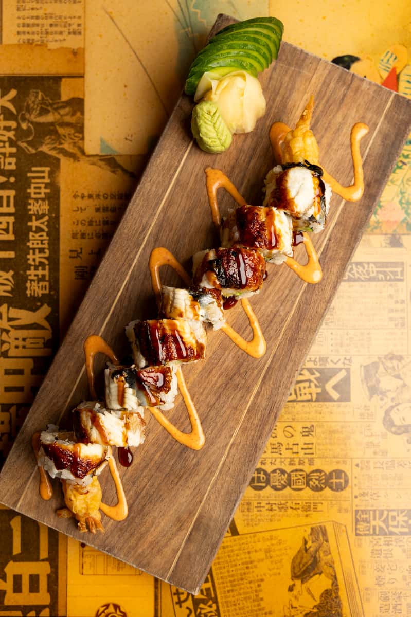 Tempura-style sushi roll drizzled with savory glaze and spicy sauce at Kapow! Noodle Bar, highlighting creative Asian fusion sushi and premium ingredients.