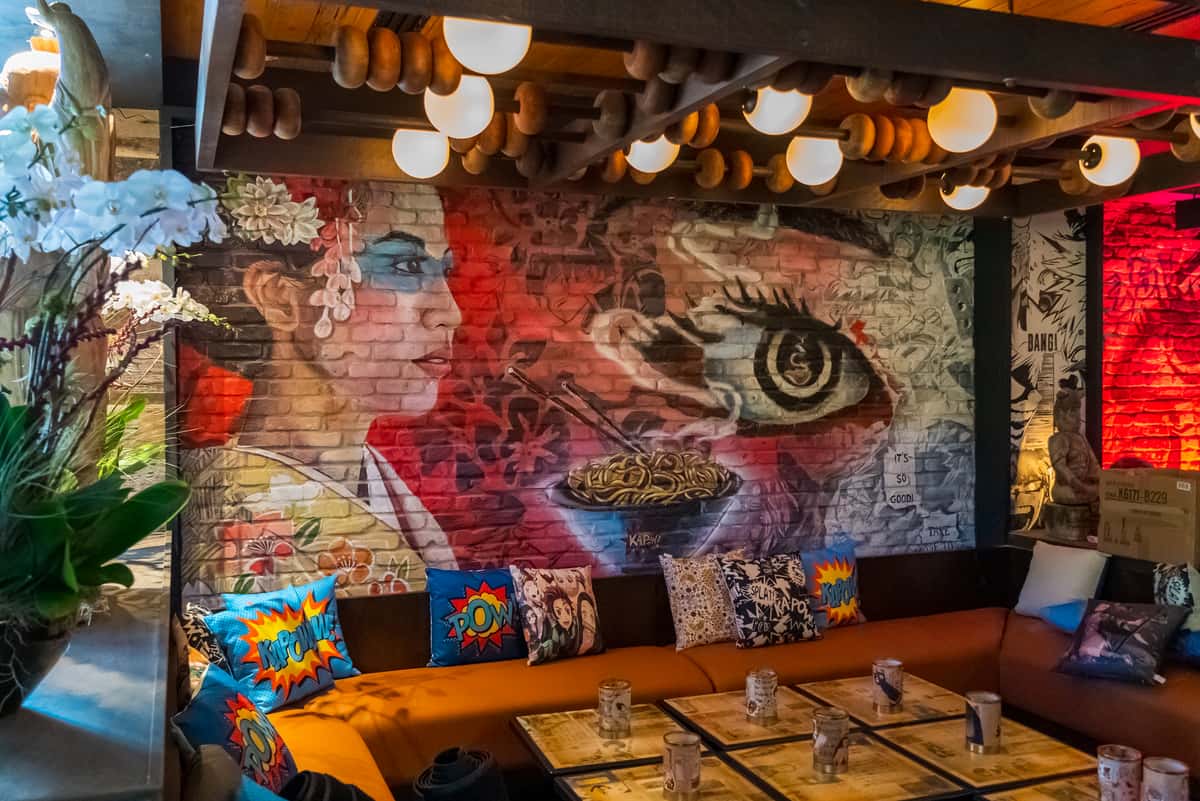 Upscale lounge seating at Kapow! Noodle Bar featuring vibrant mural artwork, modern décor, and a high-energy atmosphere ideal for dining, cocktails, and private events.