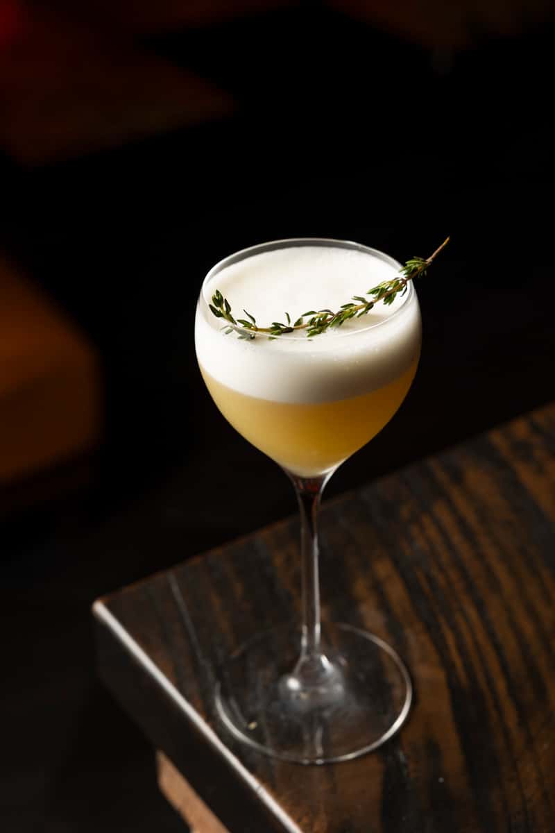 Elegant craft cocktail with velvety foam garnish served in a coupe glass at Atlantic Current restaurant