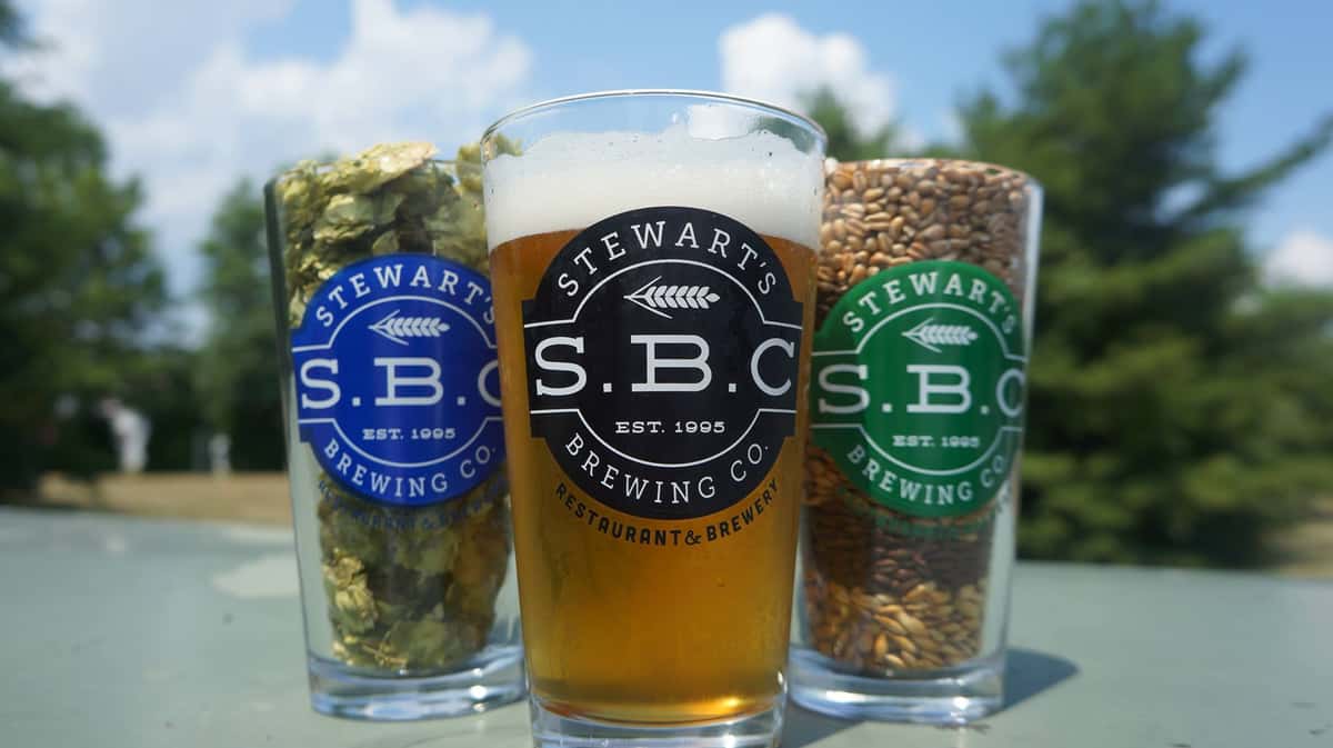 S.B.C. Logo on a pint of lite beer in the center with a pint of hops and pint of wheat to each side