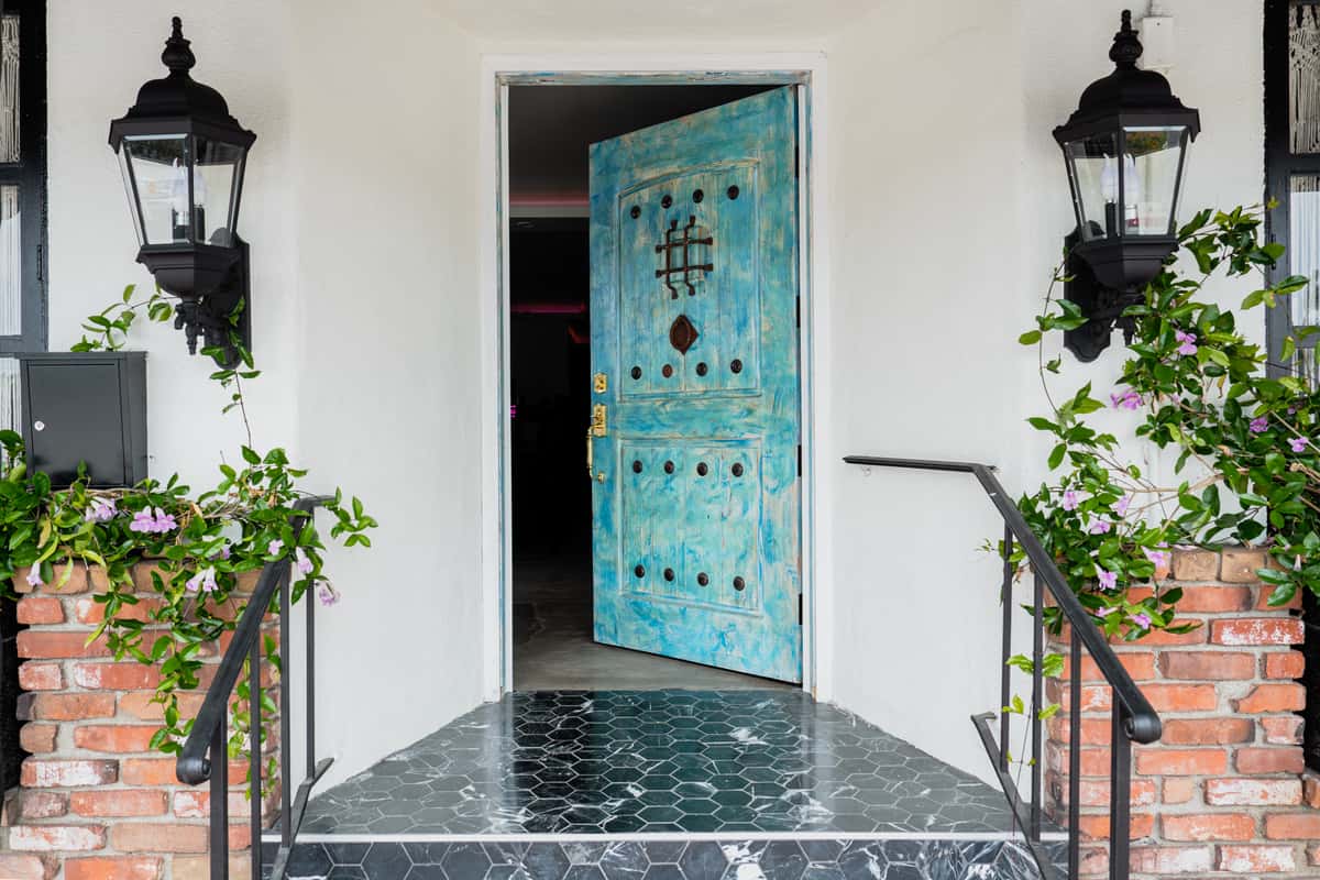 Exterior entry way of El Sueno with marble patio and light blue distressed front door.