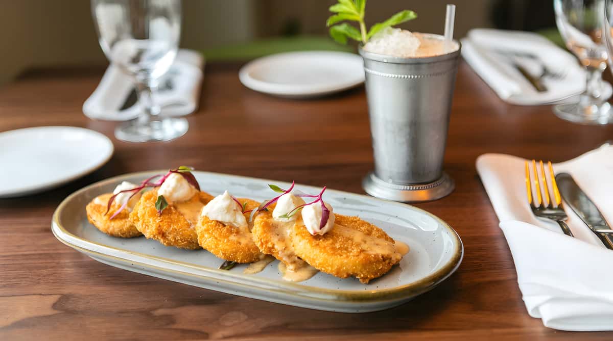 Fried green tomatoes topped with sauce and garnishes on a white plate.