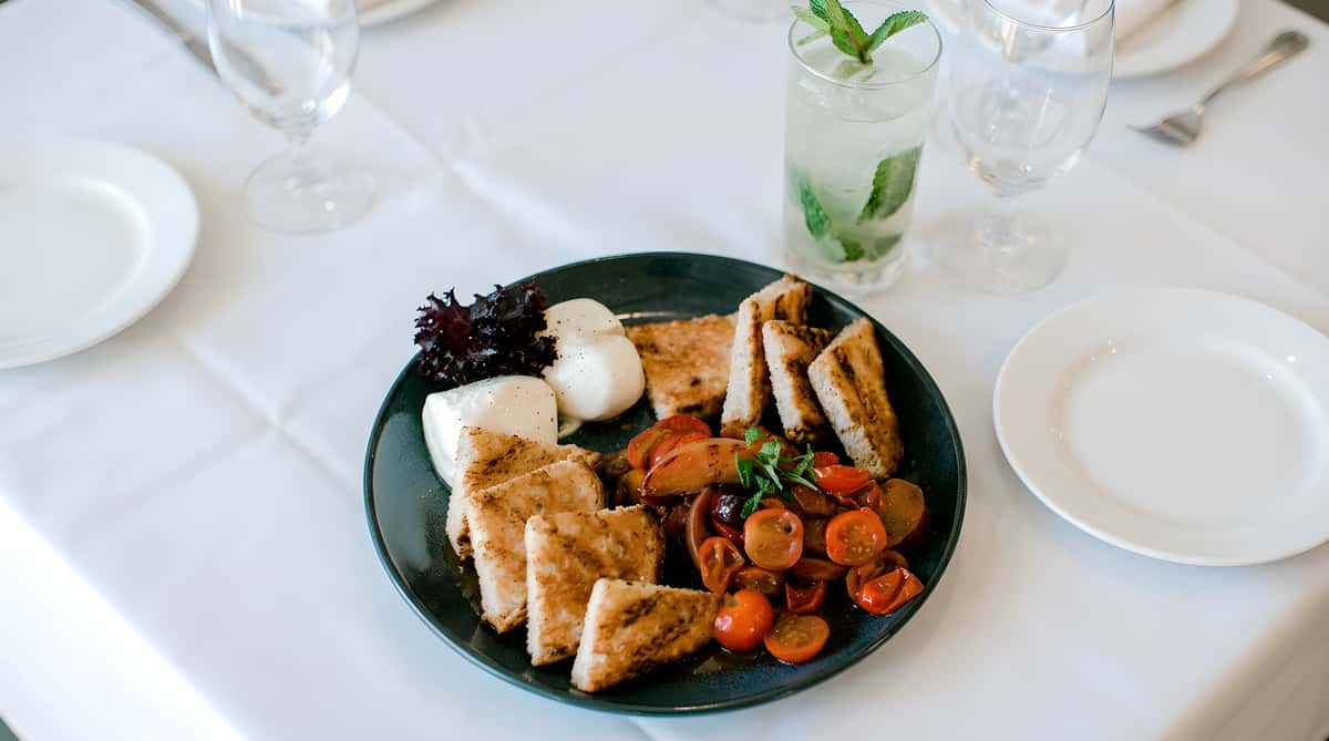 Bruschetta platter with toasted bread, tomatoes, cheese, and fresh herbs.