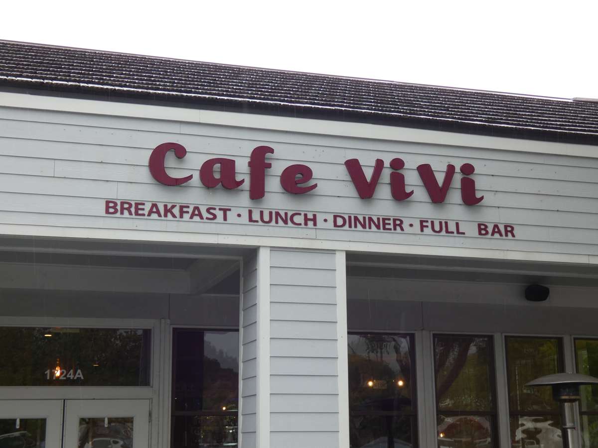 Exterior signage of Cafe ViVi, a casual eatery offering breakfast, lunch, dinner, and a full bar, displayed in bold red lettering.