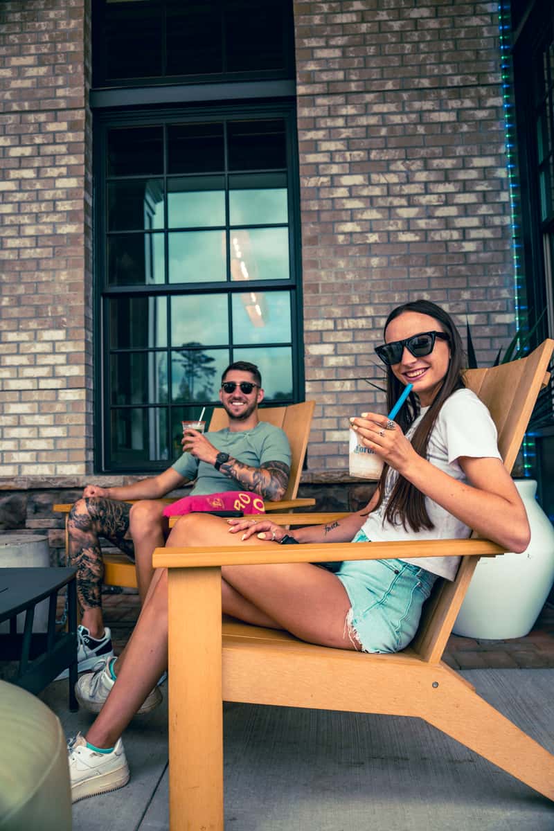 Guests relaxing outdoors on patio seating with food and drinks.
