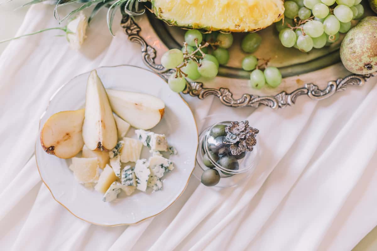 Apples, grapes, cheese on white table cloth