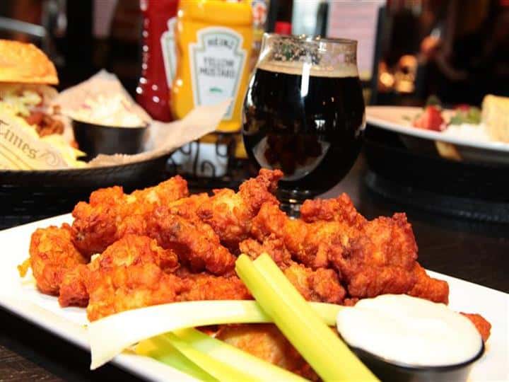 Boneless chicken wings with celery and bleu cheese dressing in front of beer and other entrees.
