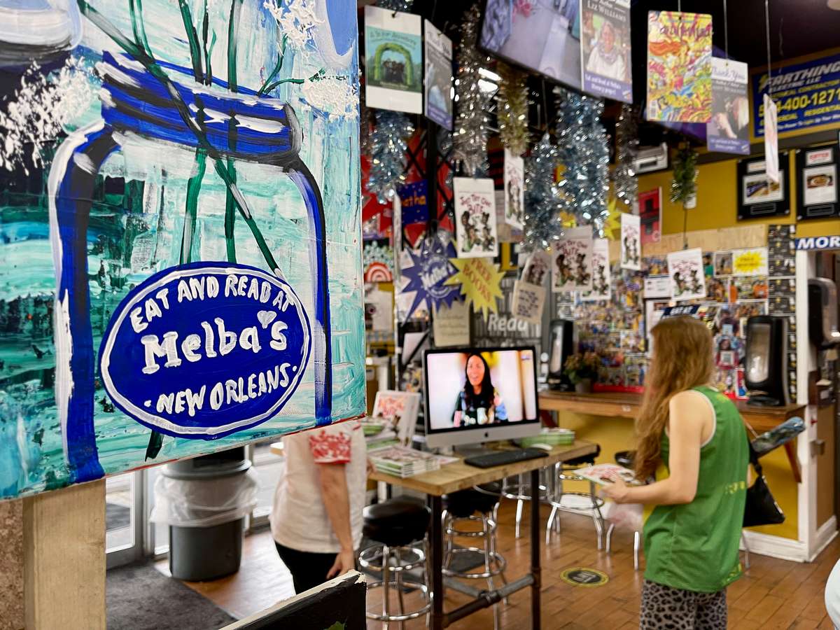 colorful "Eat and Read at Melba's New Orleans" mural inside restaurant bookstore with hanging books and cozy community reading space