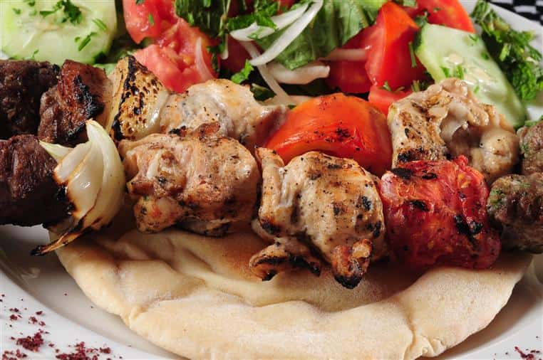 chicken kabobs over a pita with a side salad