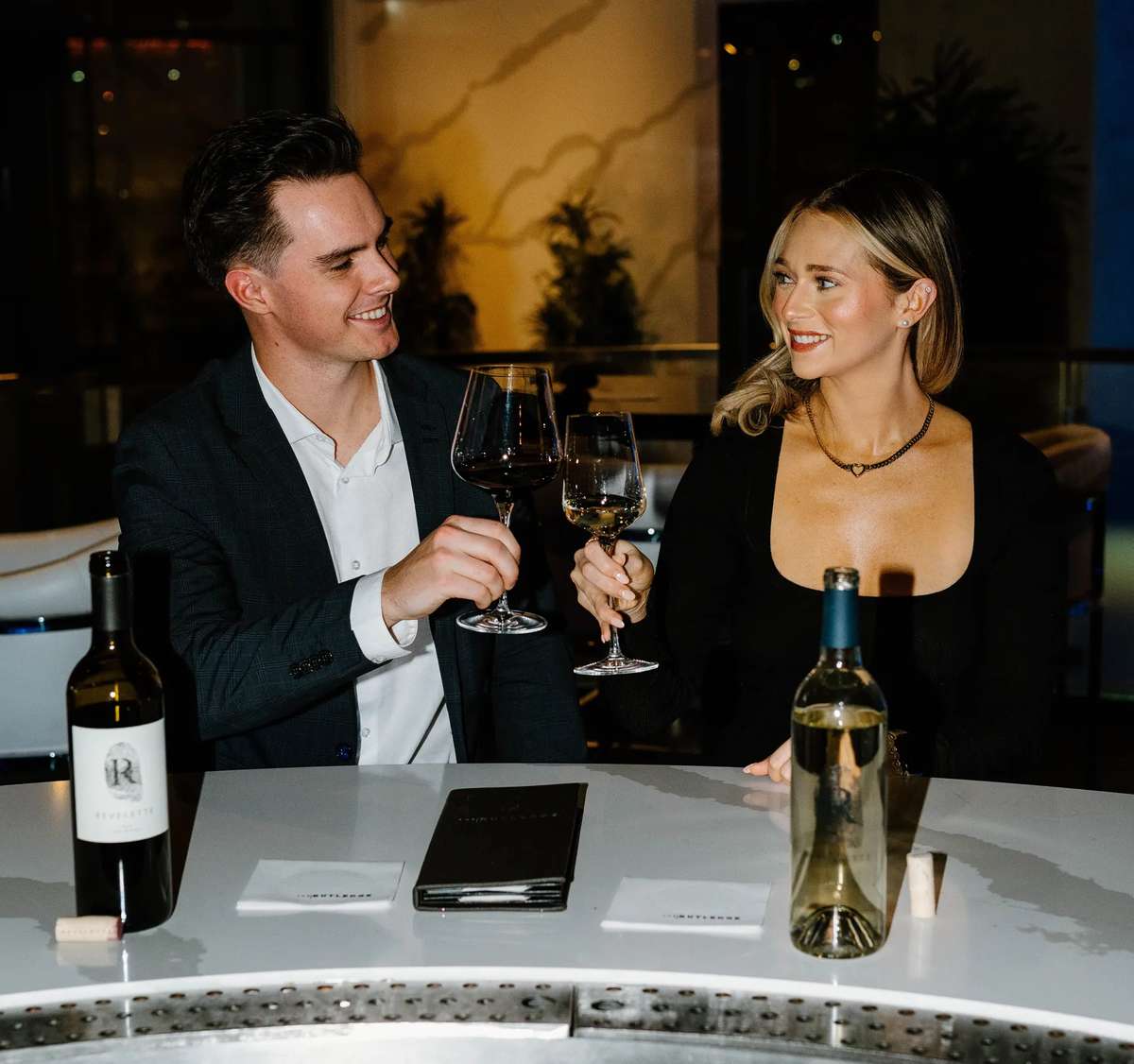 A man and woman toast wine glasses at the Rutledge Bar