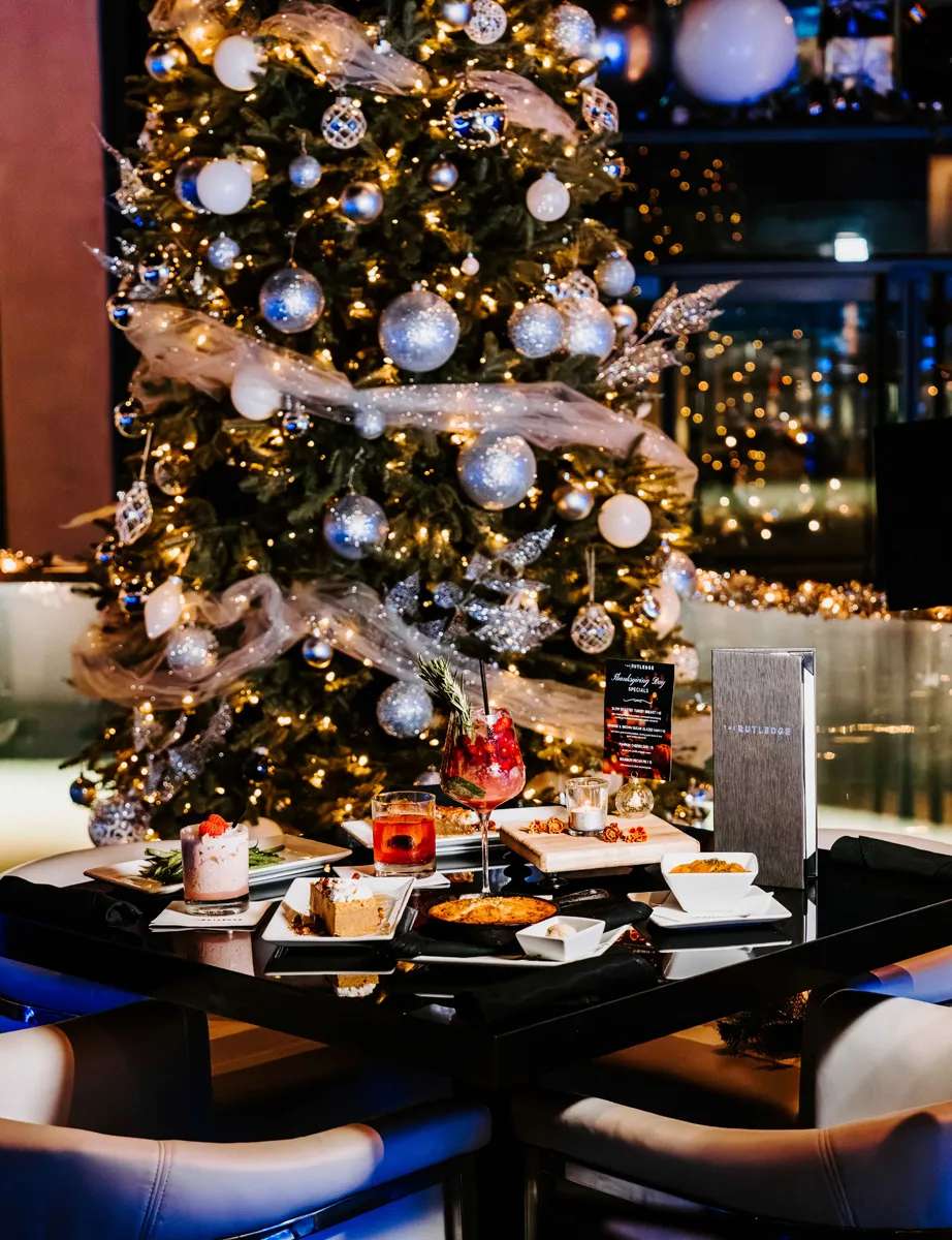 Table of food and drinks at in front of a Christmas tree at the Rutledge restaurant