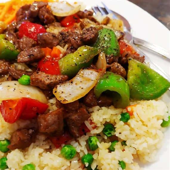 rice and steak with peas and vegetables