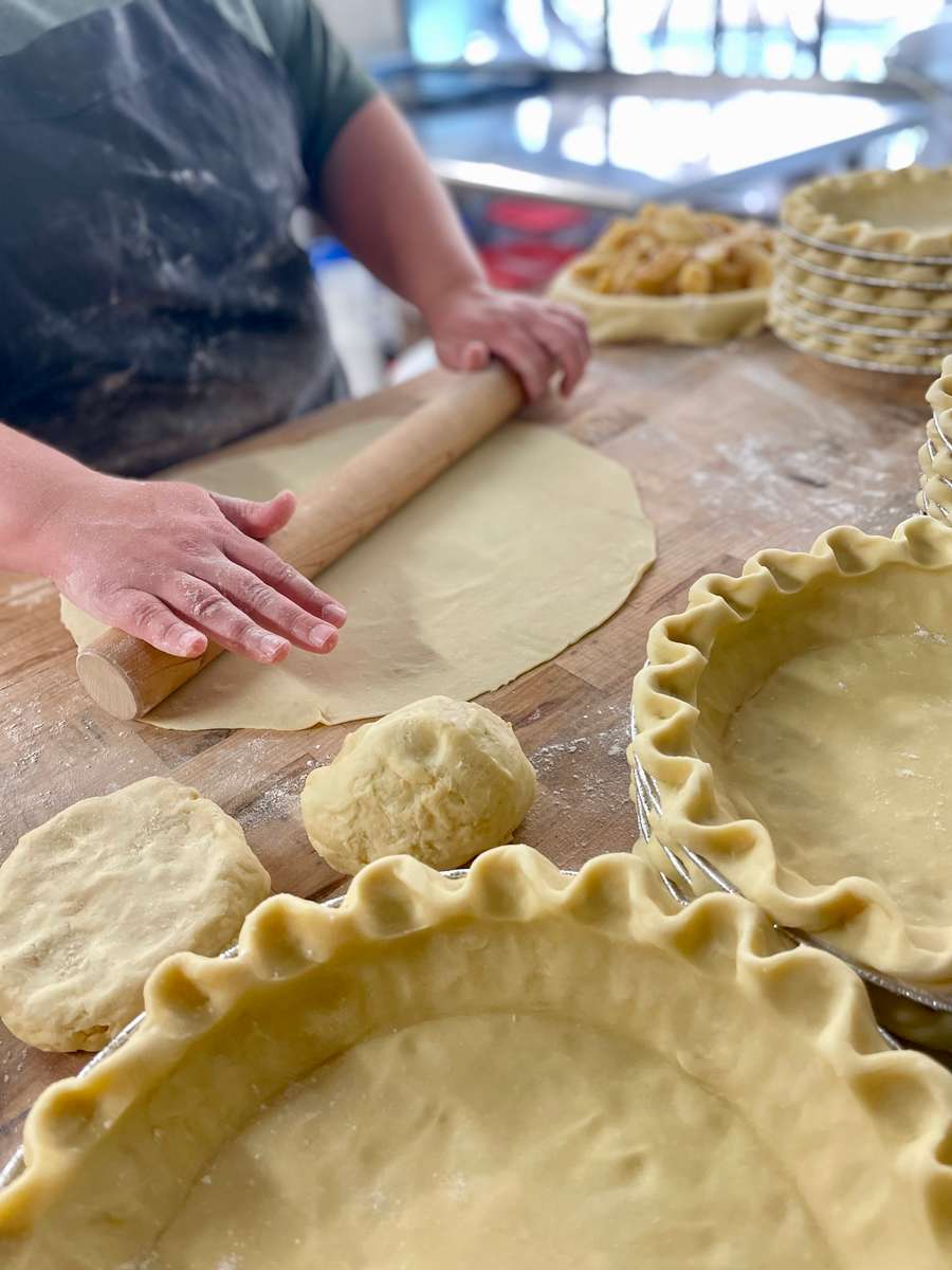 an image of a persons hands rolling out pie crust