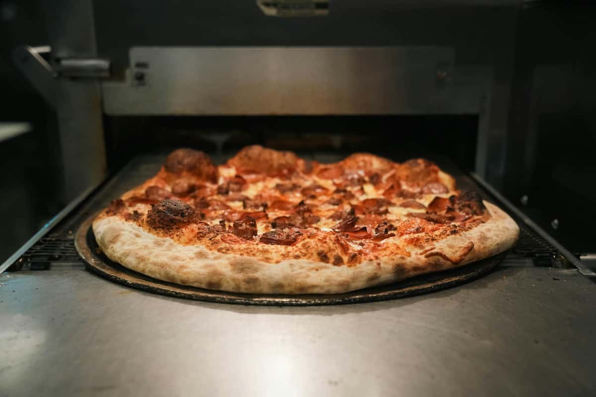 A mouth-watering pepperoni pizza baking in a commercial oven, showcasing its crispy crust and toppings.