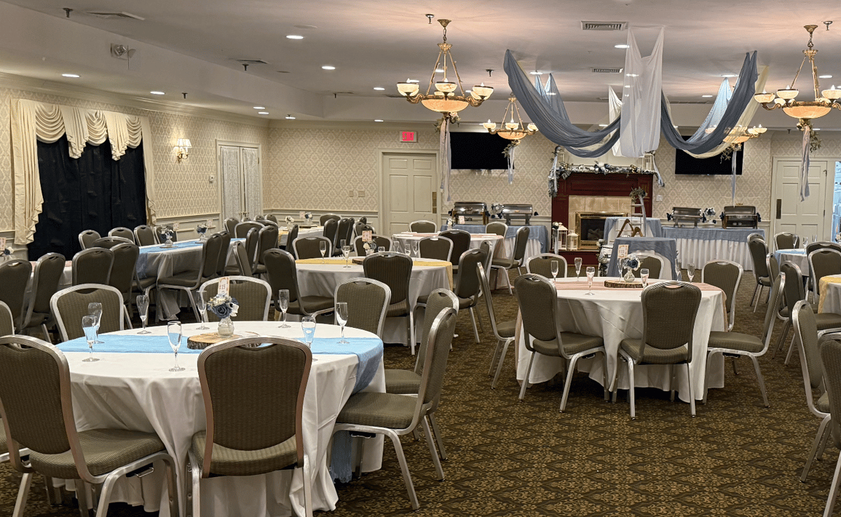 Elegant private event banquet room at Brack's Grille & Tap with round tables, chandeliers, fireplace, and beautifully decorated space for weddings, parties, and special events.