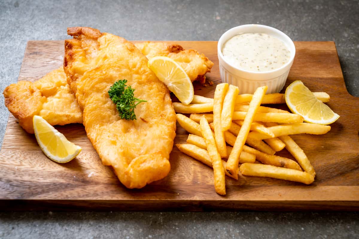 Fish and chips served with French fries, lemon wedges, and tartar sauce.