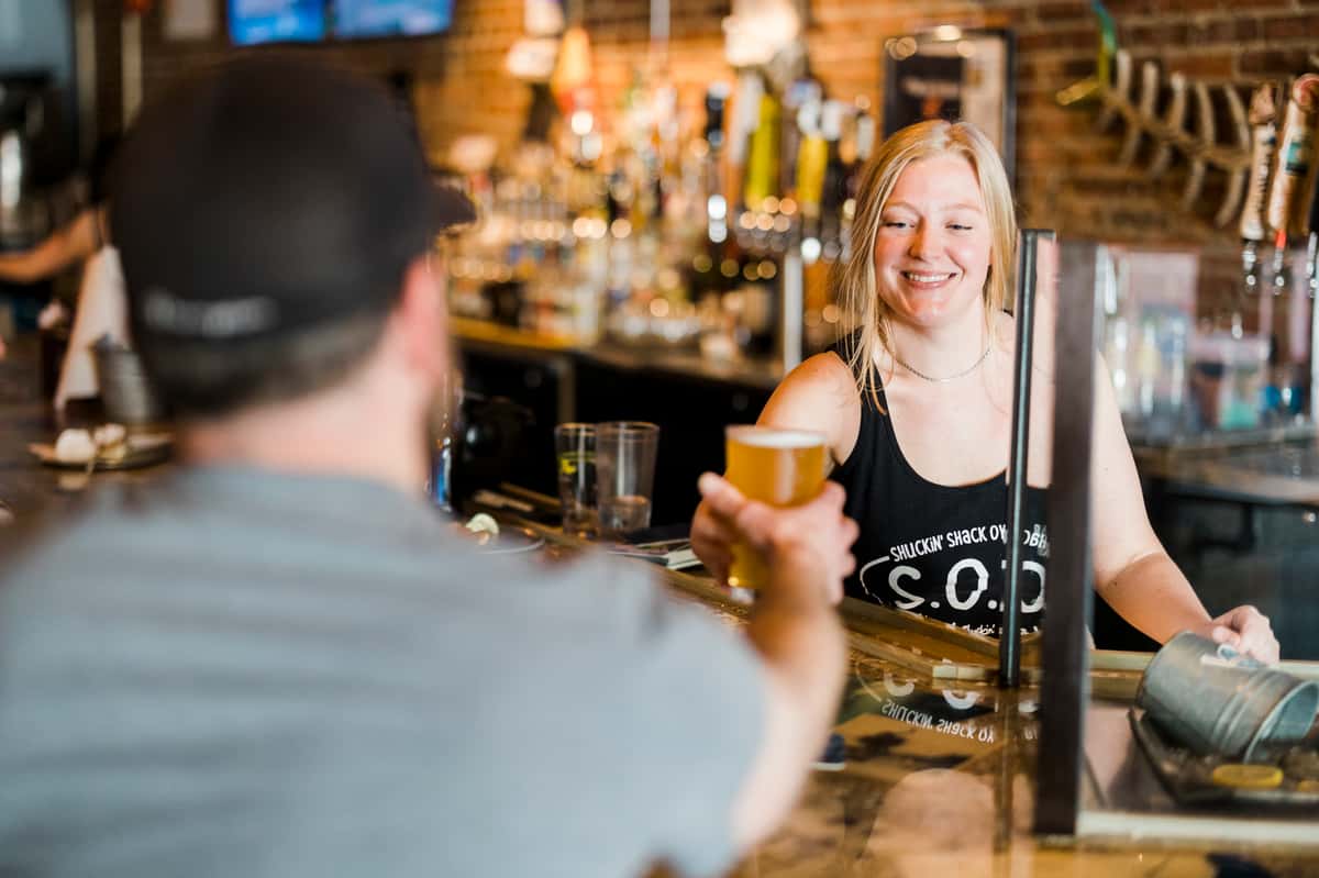 Bartender handing a customer a freshly poured beer