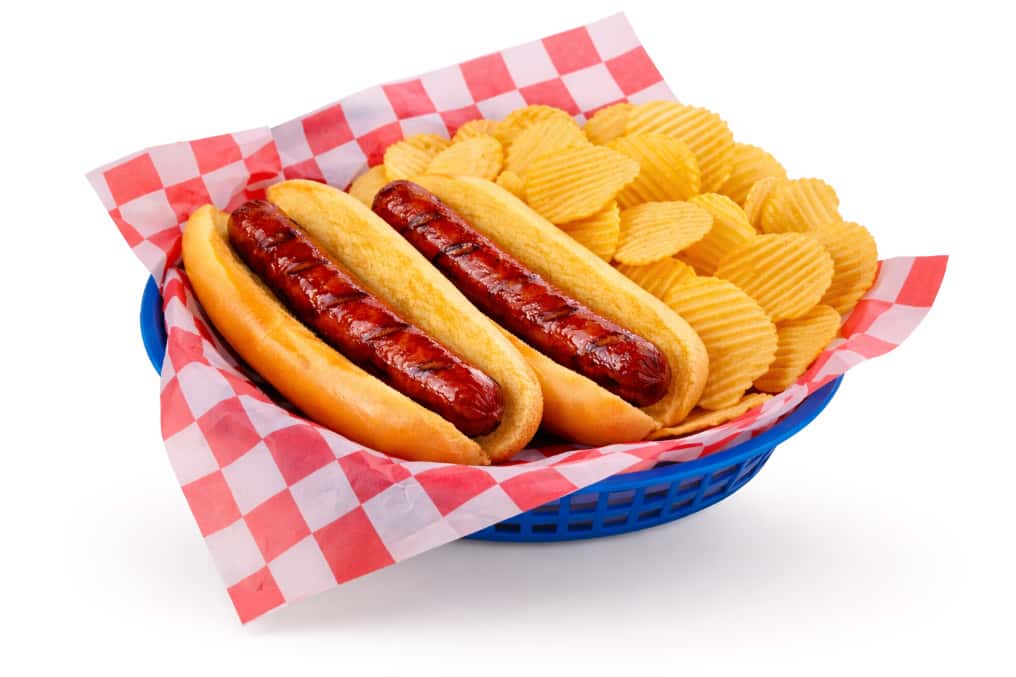 Two hot dogs served with potato chips in a basket
