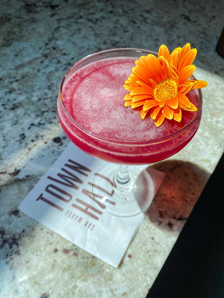 red cocktail with flower garnish