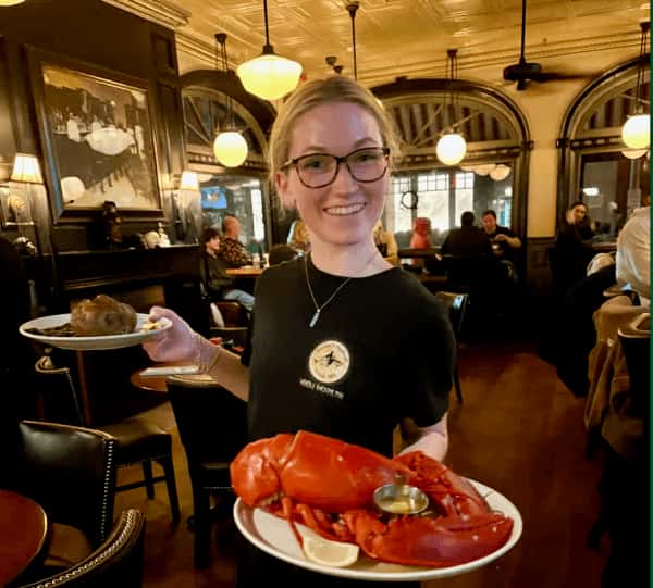 Team member serving a lobster dinner with a smile