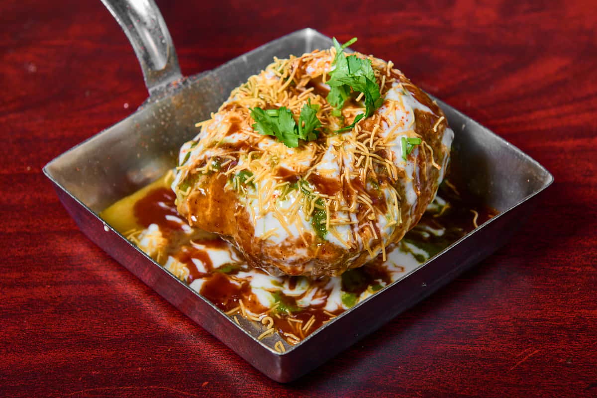 Raj kachori chaat at Dhaba Express in Parsippany, NJ, a crispy stuffed shell topped with yogurt, chutneys, sev, and fresh herbs in a vibrant North Indian street-style dish