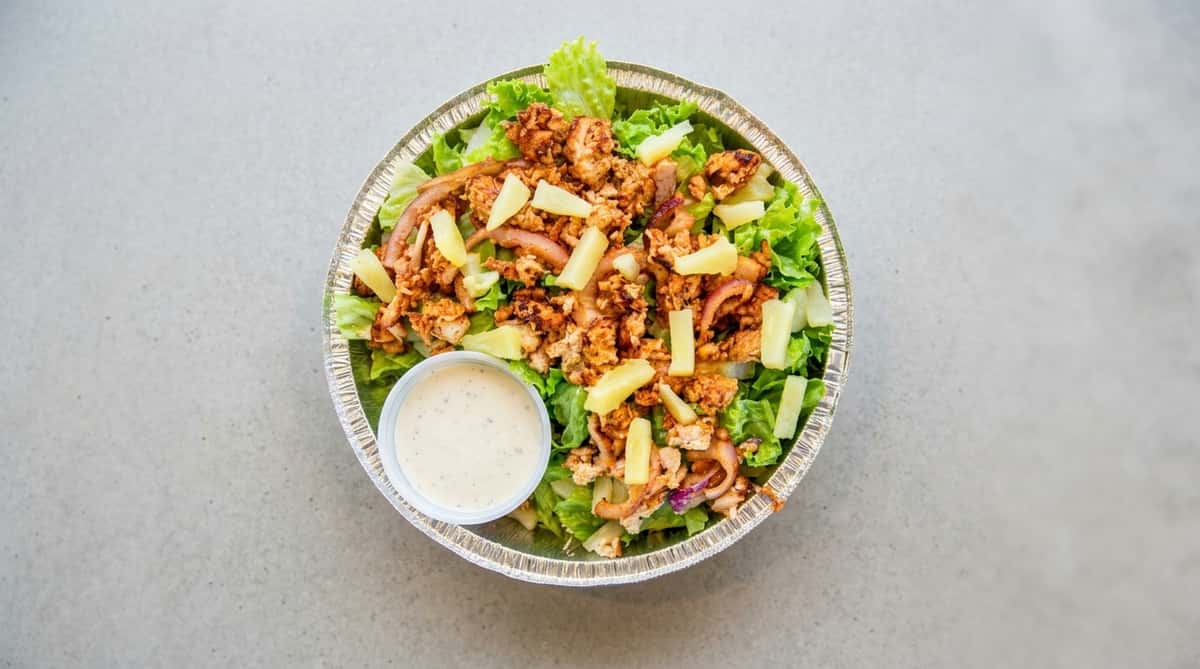 Chicken salad with pineapple and a side of dressing in a foil container